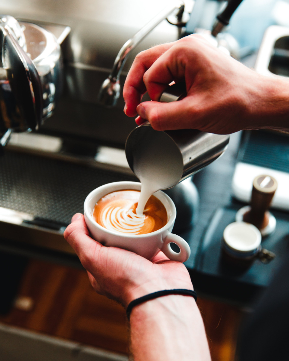 Milk being poured into a latte to make a leaf pattern