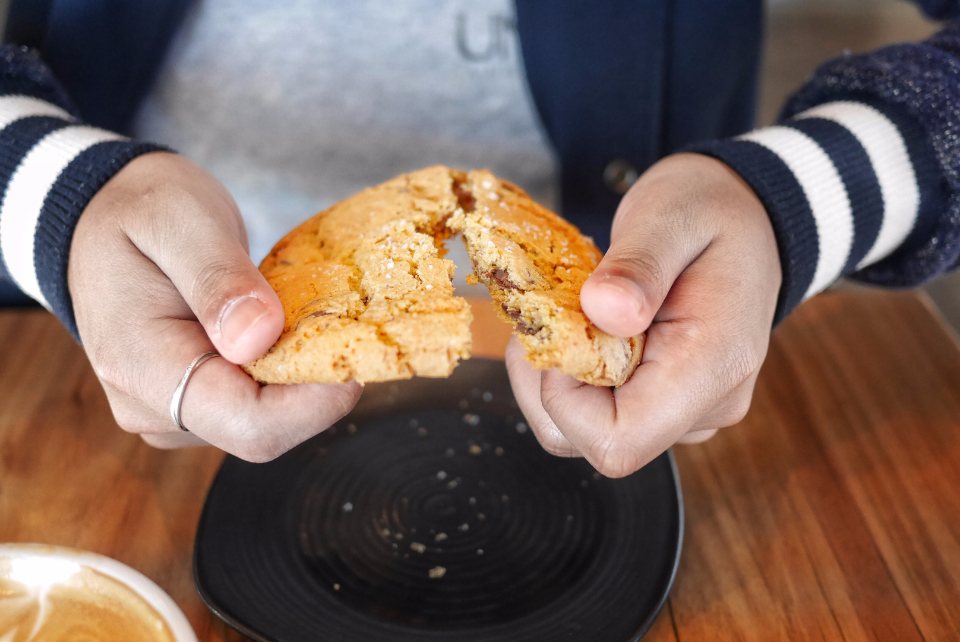 Hands breaking a soft cookie in half over a plate