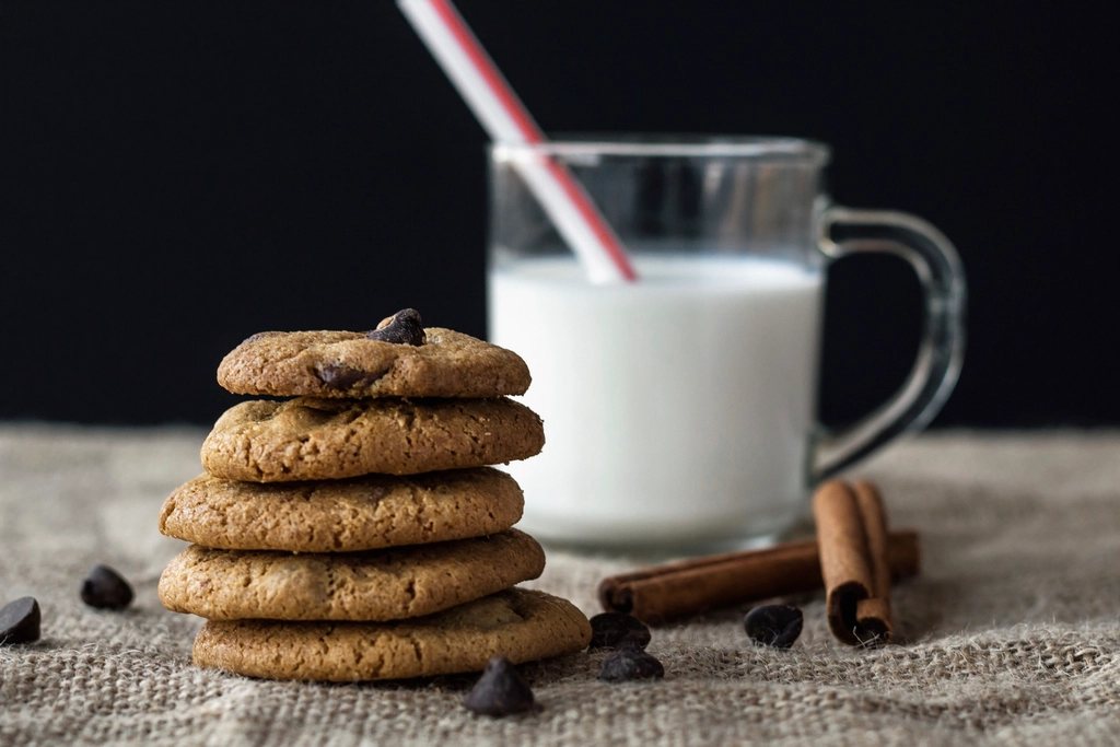 A stack of cookies beside a cold glass of milk