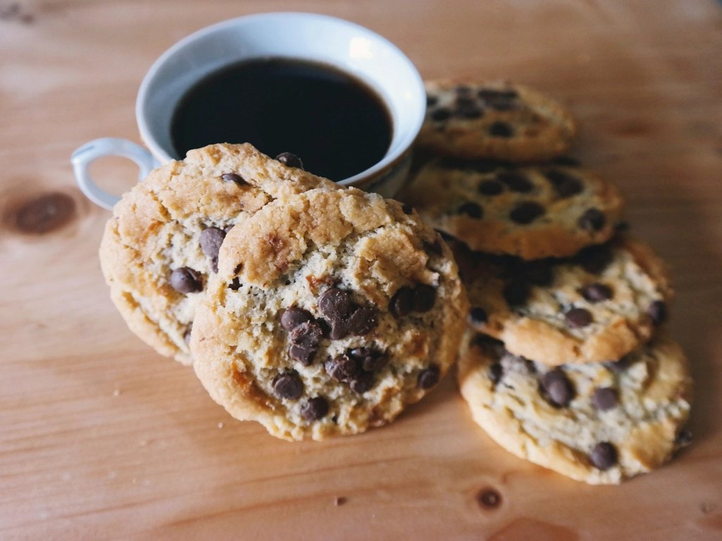 Black coffee beside a pile of chocolate chip cookies