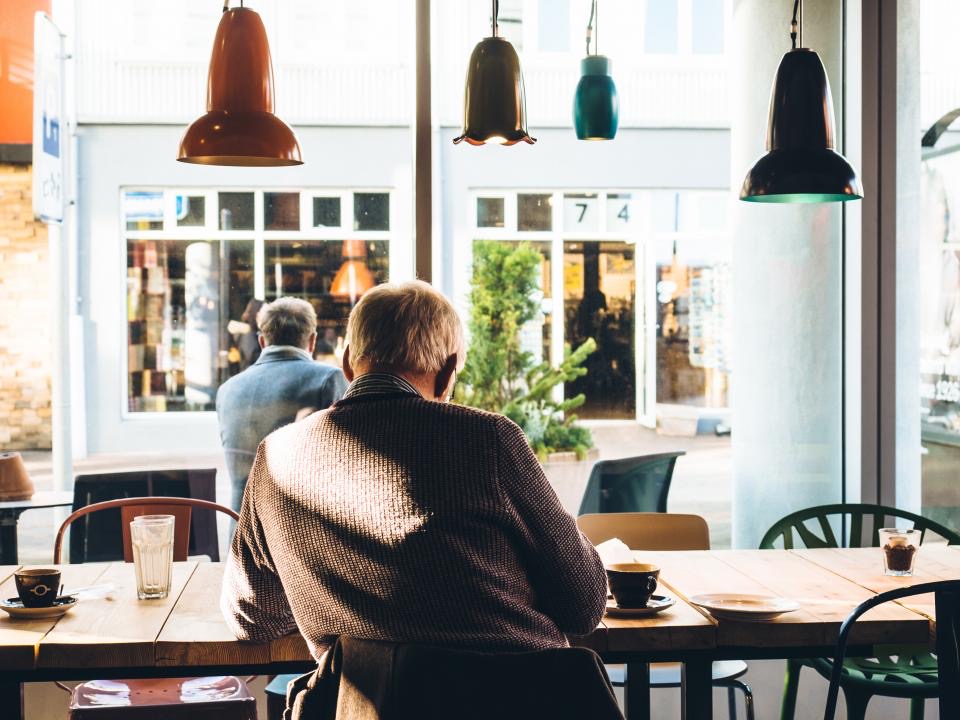 A man reading at a café table by a bright window